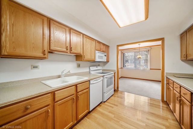 kitchen featuring light wood-type flooring, sink, white appliances, and decorative light fixtures