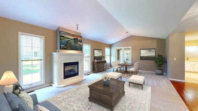 living room featuring lofted ceiling, a notable chandelier, and light hardwood / wood-style flooring