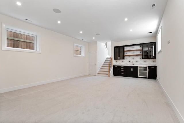 unfurnished living room featuring light carpet, wet bar, and wine cooler