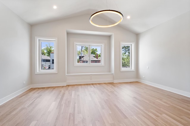 spare room featuring vaulted ceiling and light hardwood / wood-style flooring