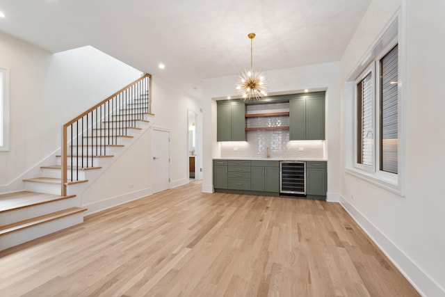 bar featuring light hardwood / wood-style flooring, green cabinets, a notable chandelier, beverage cooler, and backsplash