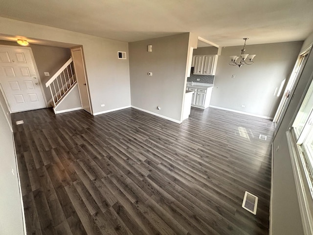 unfurnished living room featuring dark hardwood / wood-style flooring and a notable chandelier