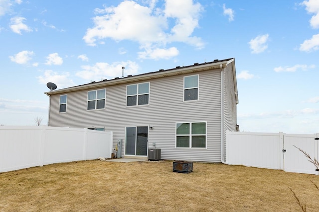 rear view of house with central AC and a lawn