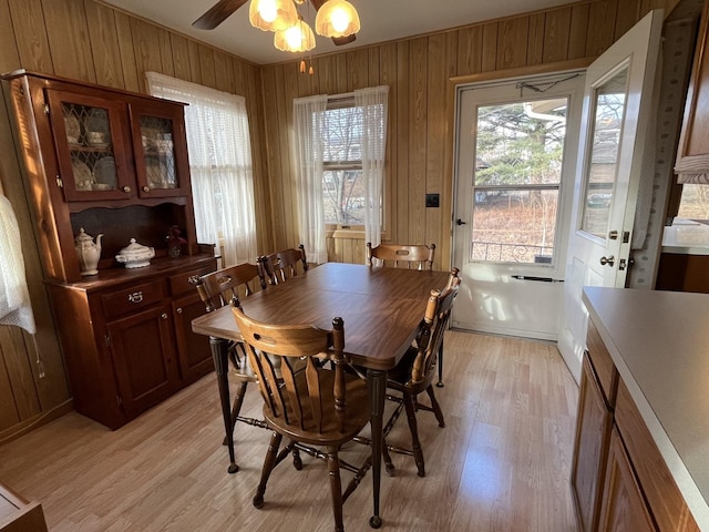 dining area with light hardwood / wood-style flooring, ceiling fan, and wood walls