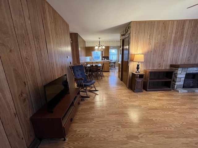 living room with a chandelier, a fireplace, and light hardwood / wood-style floors