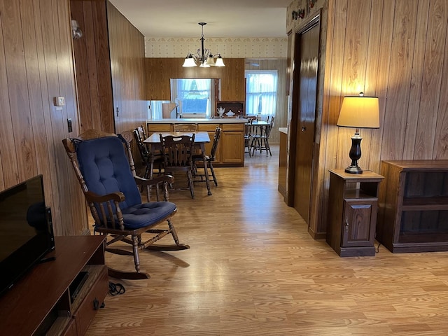 sitting room featuring a notable chandelier, light hardwood / wood-style flooring, and wooden walls