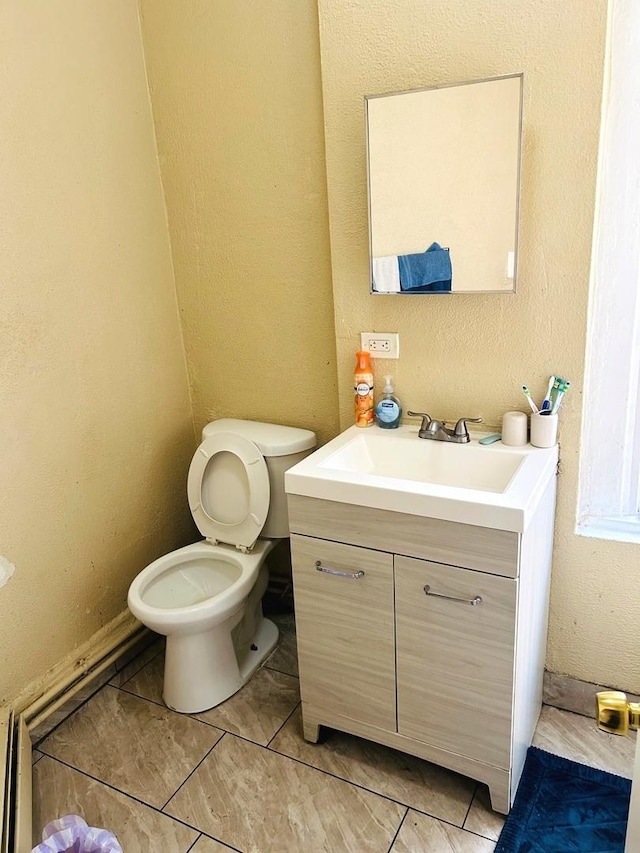 bathroom with tile patterned floors, vanity, toilet, and a baseboard radiator