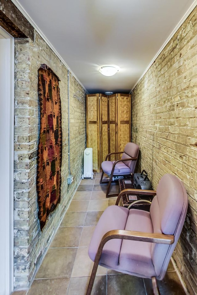 sitting room with ornamental molding, brick wall, radiator heating unit, and light tile patterned floors