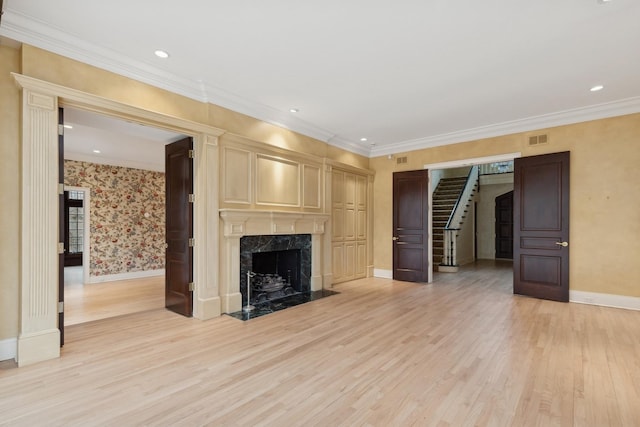 unfurnished living room with a premium fireplace, ornamental molding, and light wood-type flooring