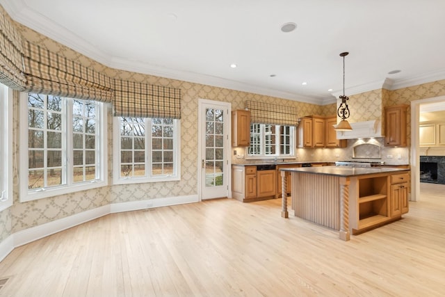 kitchen with sink, decorative light fixtures, light wood-type flooring, ornamental molding, and a kitchen island