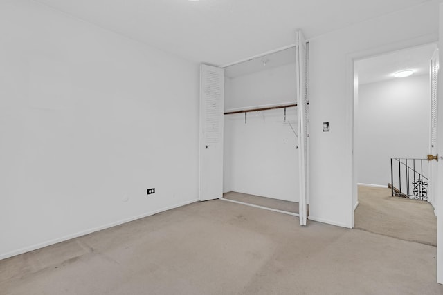 unfurnished bedroom with light carpet and a closet