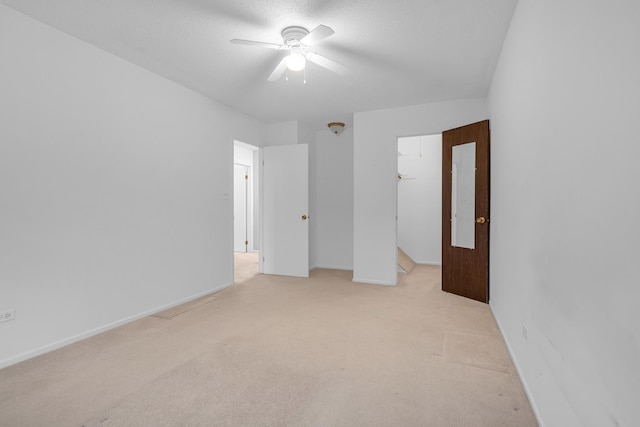 unfurnished bedroom with a spacious closet, light carpet, a textured ceiling, a closet, and ceiling fan