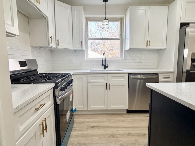 kitchen with white cabinetry, sink, decorative light fixtures, and appliances with stainless steel finishes