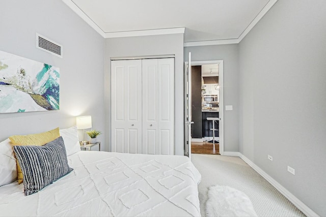 carpeted bedroom with crown molding and a closet