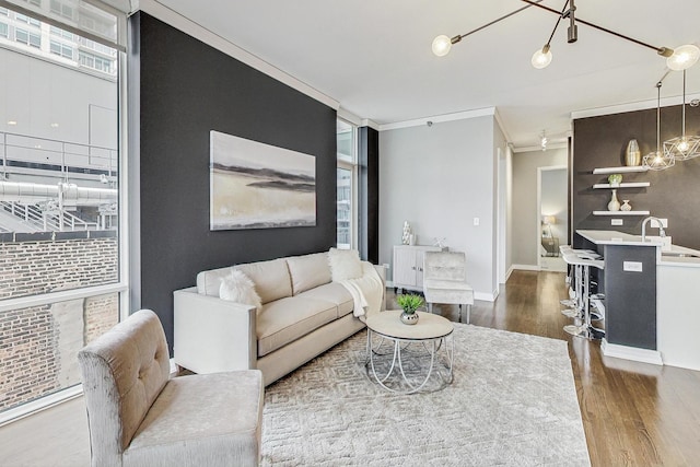 living room with crown molding, wood-type flooring, a chandelier, and a healthy amount of sunlight