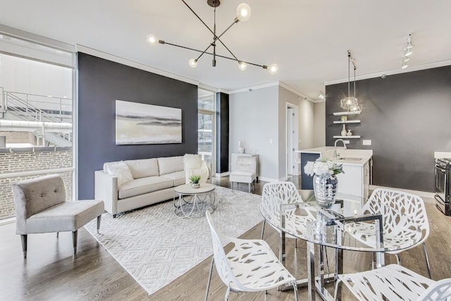 living room featuring track lighting, ornamental molding, sink, and light hardwood / wood-style floors