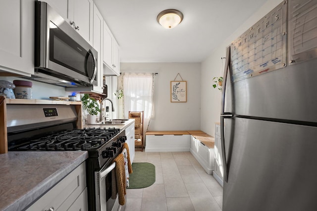 kitchen featuring light tile patterned flooring, stainless steel appliances, sink, and white cabinets