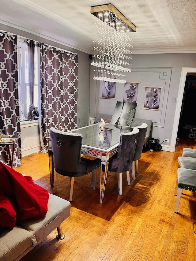 dining room with ornamental molding, wood-type flooring, a textured ceiling, and an inviting chandelier