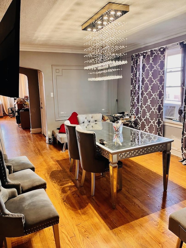 dining area featuring crown molding, cooling unit, a notable chandelier, light hardwood / wood-style floors, and a textured ceiling