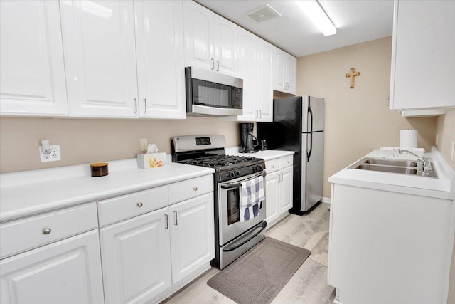 kitchen featuring white cabinetry, sink, light wood-type flooring, and appliances with stainless steel finishes