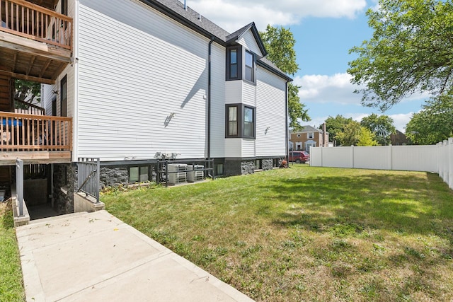 view of property exterior featuring cooling unit, a lawn, and fence