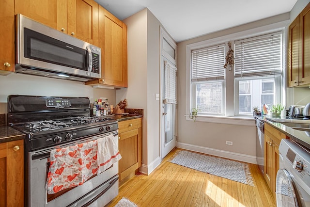 kitchen featuring sink, washer / dryer, light wood-type flooring, and appliances with stainless steel finishes