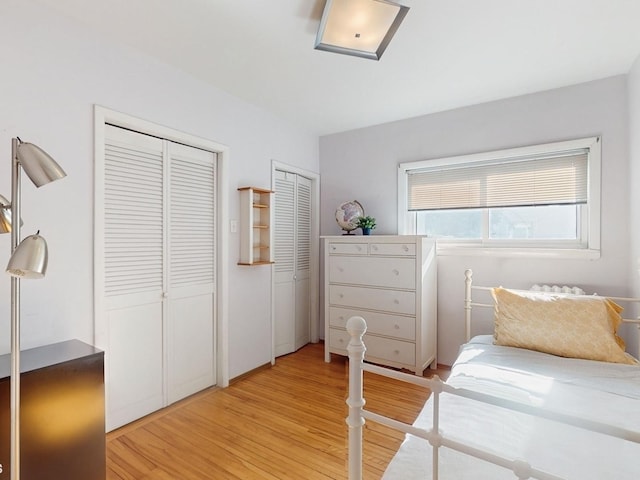 bedroom with multiple closets and light wood-type flooring