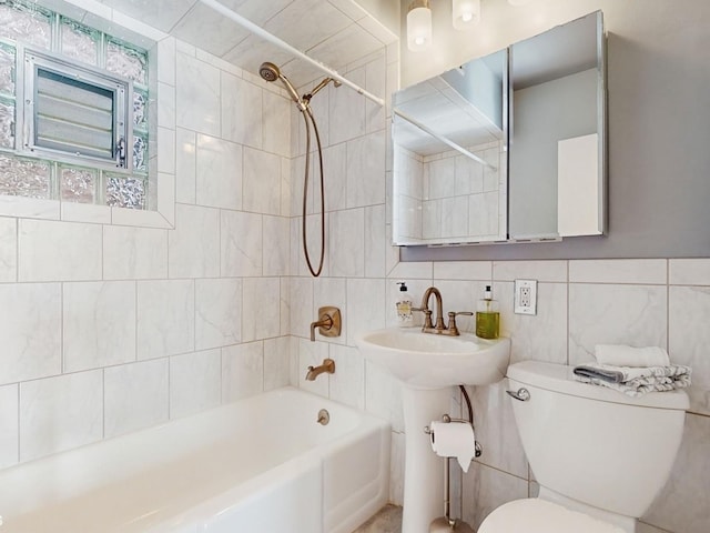 full bathroom with tiled shower / bath, sink, tile walls, and toilet