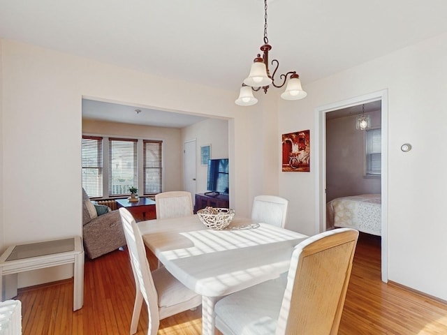 dining space with hardwood / wood-style floors and a chandelier