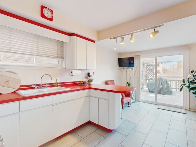 kitchen featuring sink, kitchen peninsula, and white cabinets