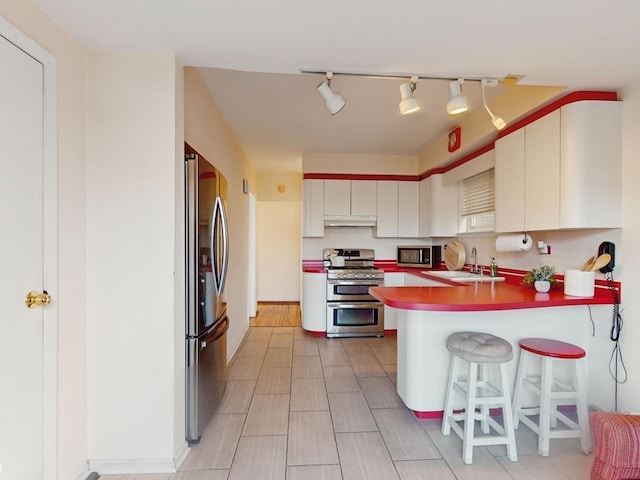 kitchen with sink, white cabinets, a kitchen bar, kitchen peninsula, and stainless steel appliances