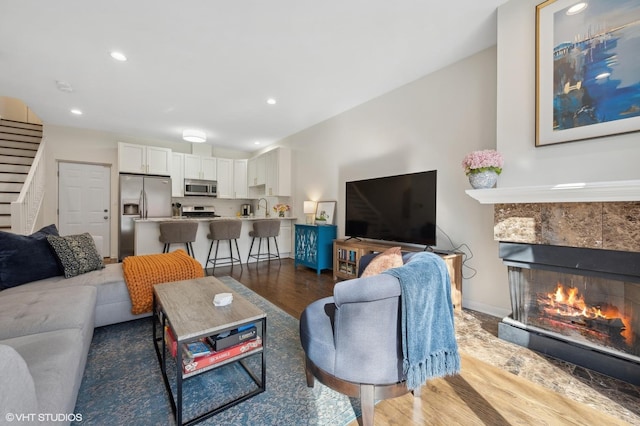 living room with wood-type flooring, sink, and a tile fireplace