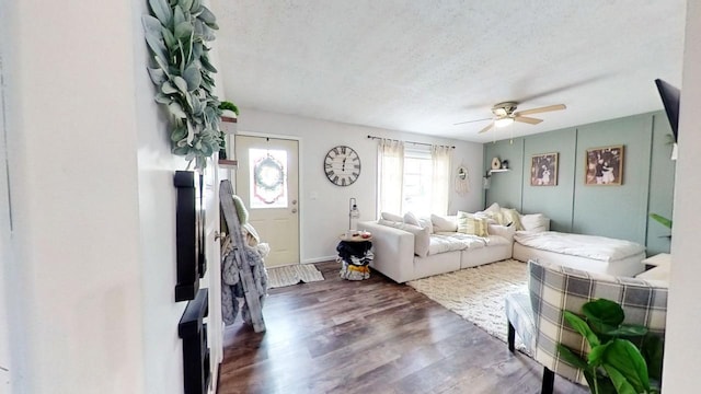 living room featuring ceiling fan, dark wood-type flooring, and a textured ceiling