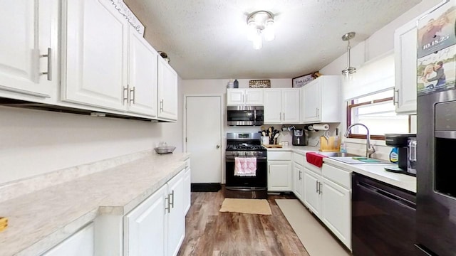 kitchen featuring appliances with stainless steel finishes, sink, white cabinets, hanging light fixtures, and a textured ceiling