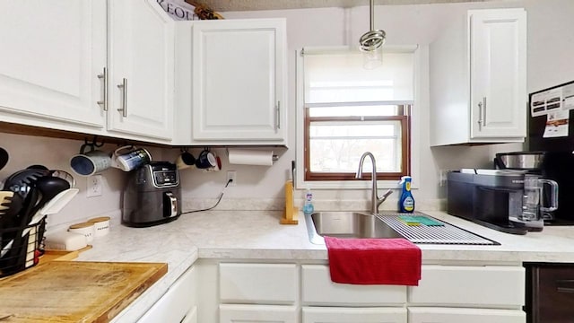 kitchen with white cabinetry, sink, and hanging light fixtures