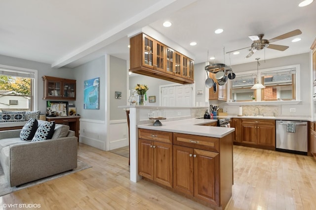 kitchen featuring decorative light fixtures, light hardwood / wood-style flooring, kitchen peninsula, and appliances with stainless steel finishes