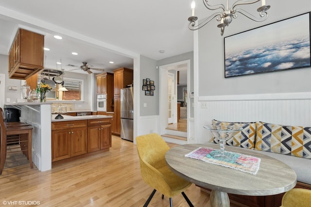 dining area featuring ceiling fan with notable chandelier and light hardwood / wood-style flooring