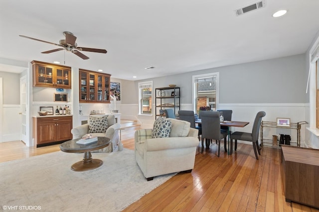 living room with ceiling fan, bar, and light hardwood / wood-style flooring