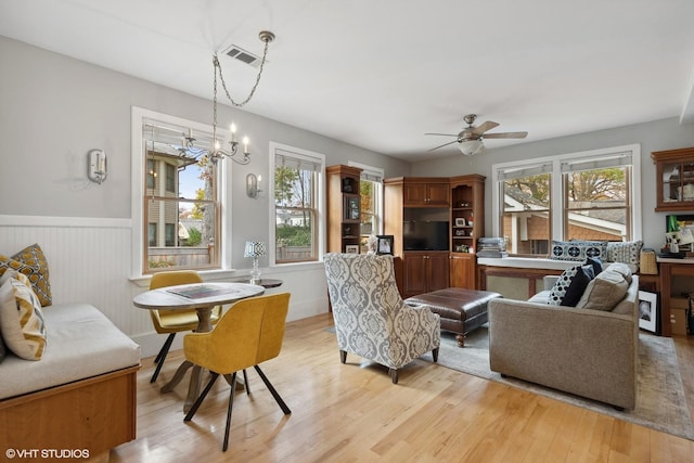 living room featuring ceiling fan with notable chandelier and light hardwood / wood-style flooring