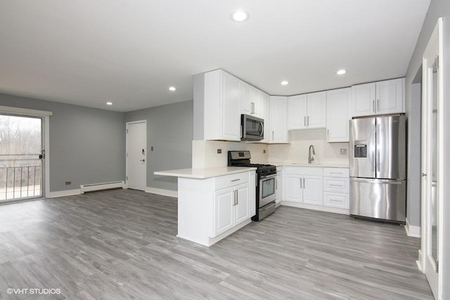 kitchen featuring sink, white cabinetry, a baseboard radiator, appliances with stainless steel finishes, and kitchen peninsula