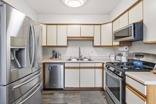 kitchen featuring appliances with stainless steel finishes, sink, white cabinets, and dark hardwood / wood-style flooring