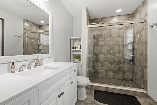 bathroom featuring tile patterned floors, vanity, toilet, and a shower with door