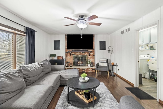 living room featuring a brick fireplace, washer / clothes dryer, dark hardwood / wood-style floors, and ceiling fan