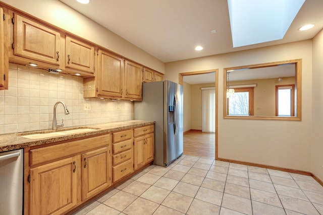 kitchen with light brown cabinetry, sink, light tile patterned floors, appliances with stainless steel finishes, and decorative backsplash