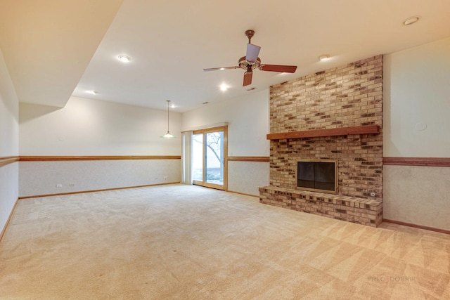 unfurnished living room with a brick fireplace, ceiling fan, and carpet flooring