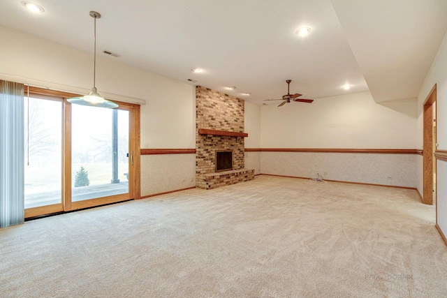 unfurnished living room featuring ceiling fan, a fireplace, and light carpet