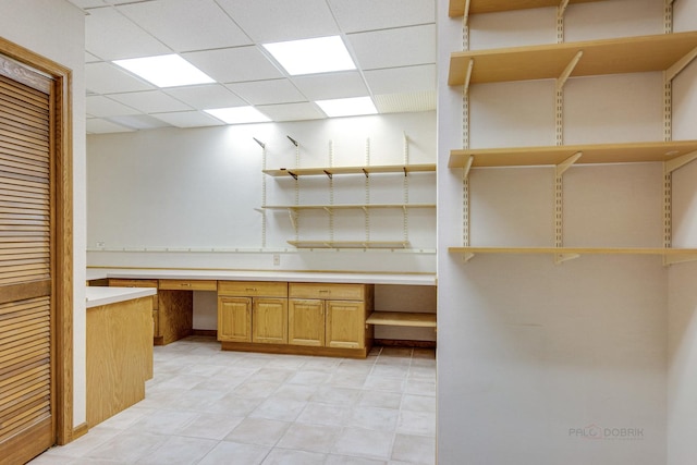 unfurnished office featuring a drop ceiling and built in desk