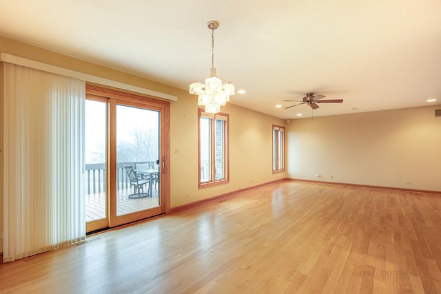 unfurnished room featuring ceiling fan with notable chandelier and light hardwood / wood-style flooring