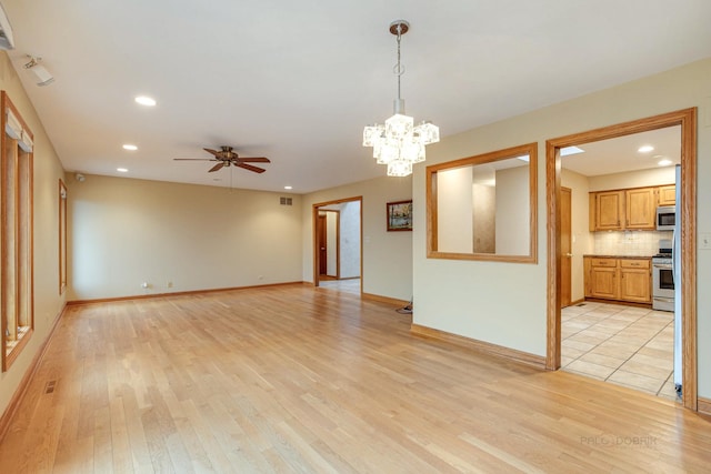 interior space featuring ceiling fan with notable chandelier and light wood-type flooring