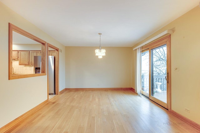 spare room with an inviting chandelier and light hardwood / wood-style flooring